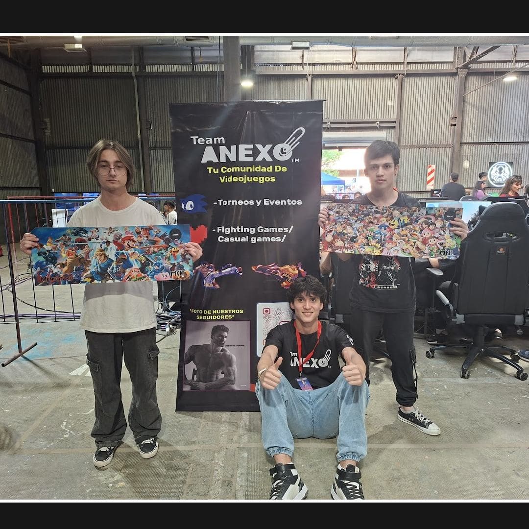 Los ganadores del torneo de Smash posando con sus premios frente al banner de Team Anexo